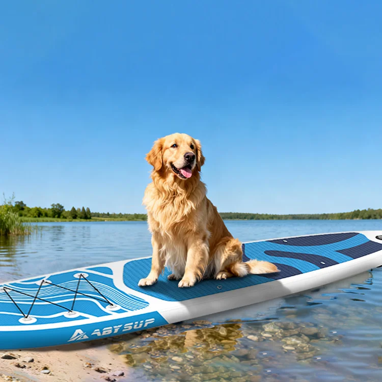 Golden retriever sitting on a blue paddleboard at the edge of a calm lake with a clear blue sky.