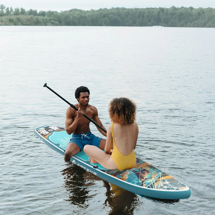 Two people sitting on a paddleboard in a lake, with one wearing a yellow swimsuit and holding a paddle.
