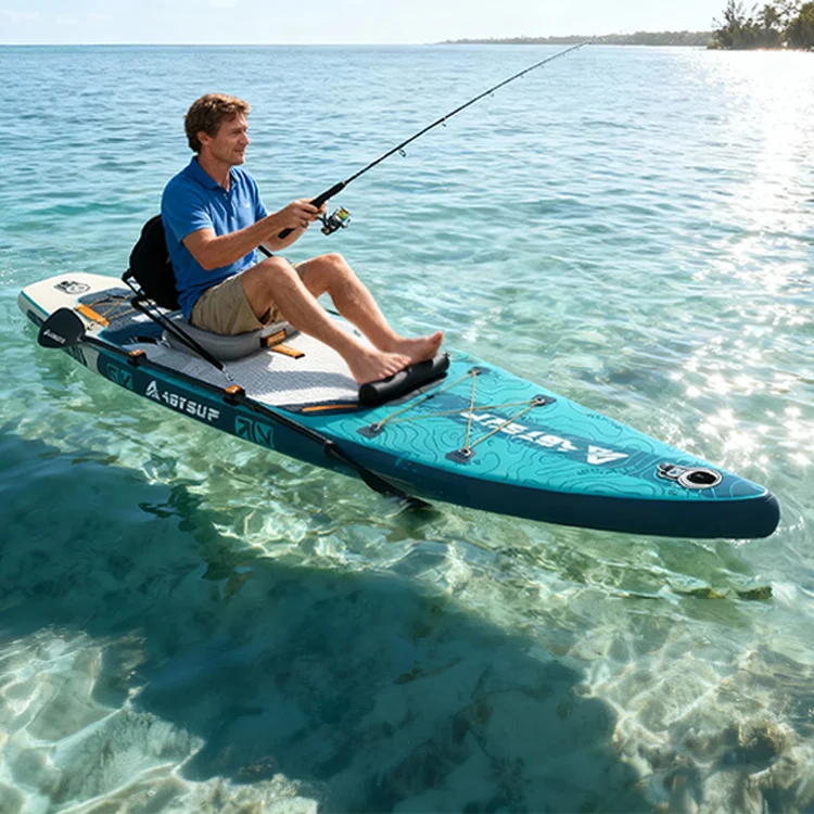 A man in a blue shirt and shorts is fishing on a paddleboard in clear, shallow water under a sunny sky.