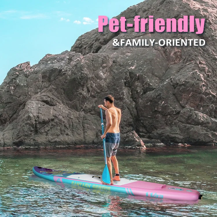 Man paddleboarding on a brightly colored board near a rocky coastline with clear water, under a blue sky.