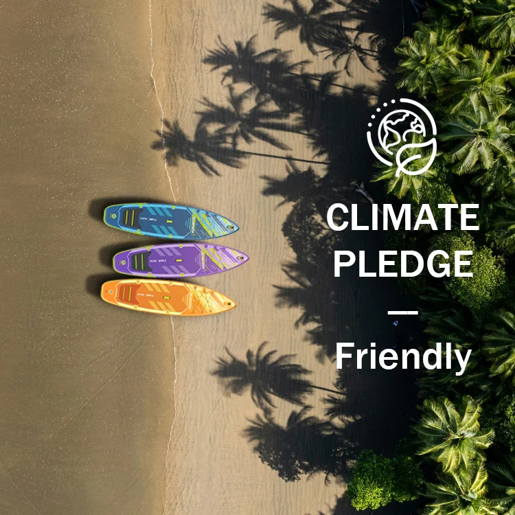 Overhead view of three colorful paddleboards on a sandy beach bordered by lush green palm trees, with a Climate Pledge logo and text.